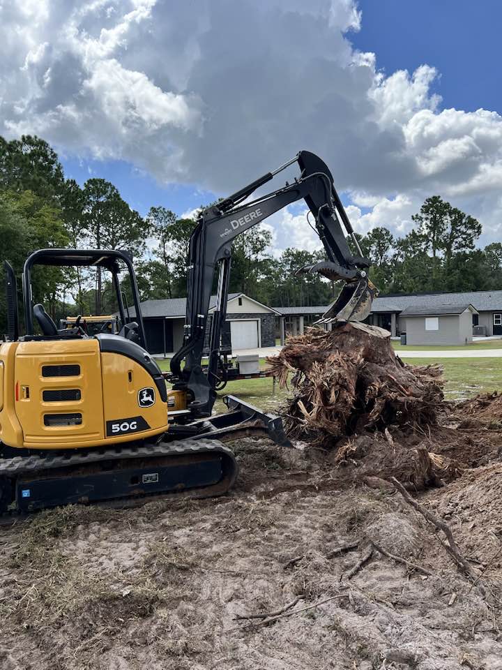 Compact excavator removing roots during site preparation